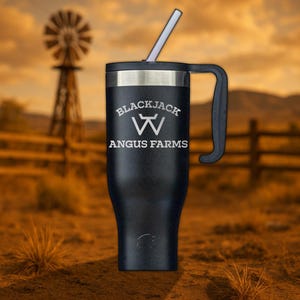 May include: Black travel mug with a black handle and a silver lid. The mug has a white logo that says "Blackjack Angus Farms" with a stylized "W" in the center.