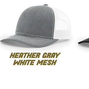 May include: Three trucker hats in different color combinations. The first hat is heather gray with a black mesh back. The second hat is heather gray with a white mesh back. The third hat is black with a black mesh back.