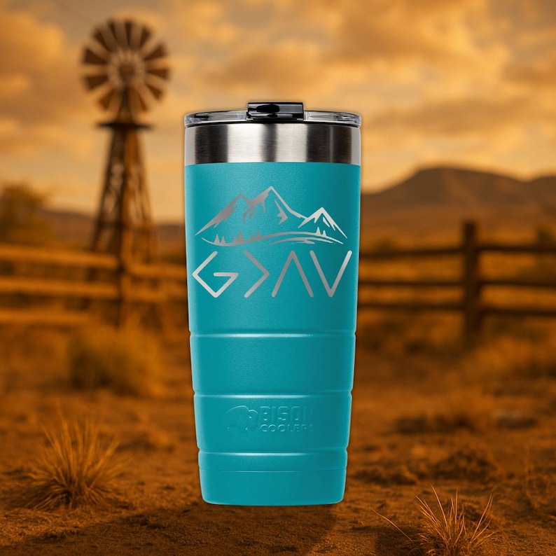 Op de afbeelding: Een turquoise roestvrijstalen tumbler met een zilveren deksel. De tumbler heeft een bergketenontwerp en de woorden "God is groter dan" in zilveren letters.