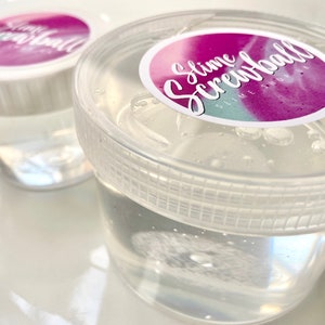 May include: Two clear plastic containers filled with clear slime. The containers have white lids with a pink and blue sticker that says "Slime Screwball Slime Shop".