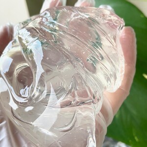 May include: A clear, translucent gel substance with a smooth, viscous texture. The gel is being held in a gloved hand.
