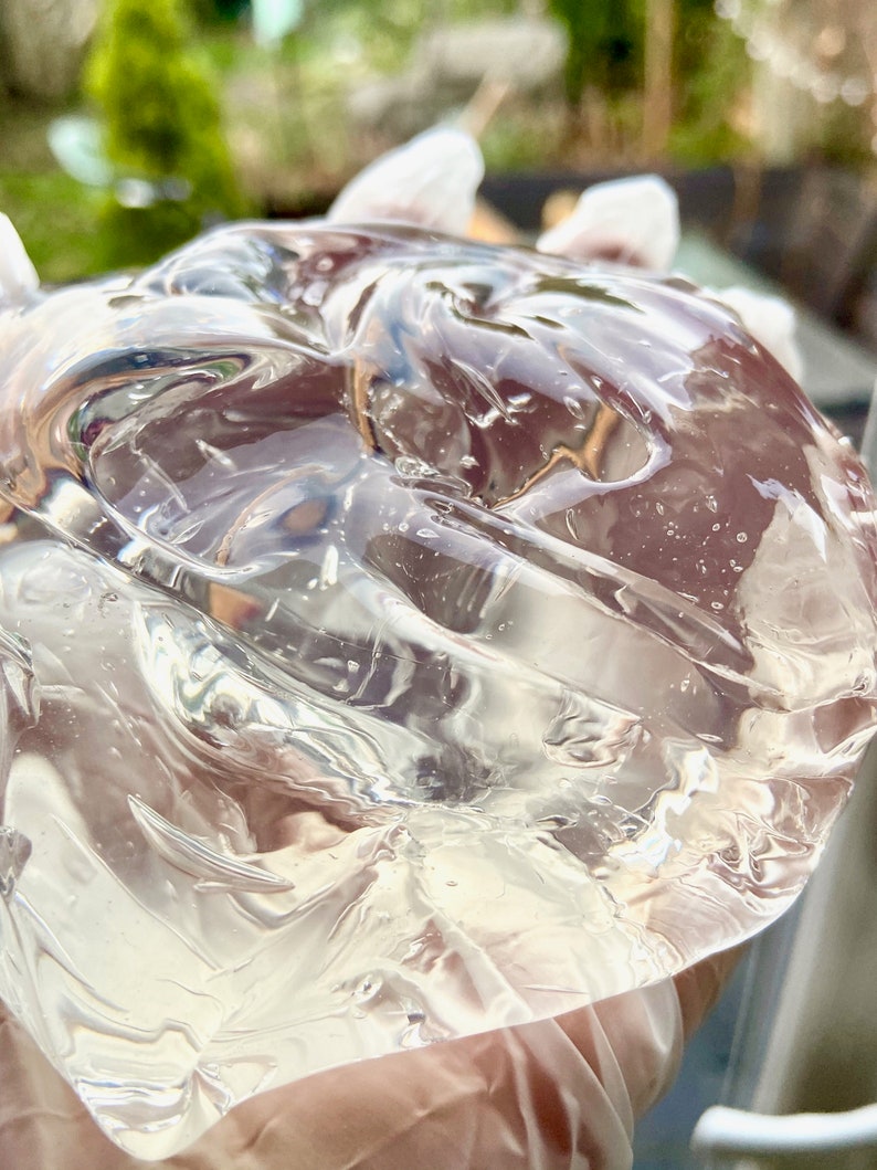 May include: A clear, translucent gel with a smooth, rippled surface. The gel is being held in a gloved hand.