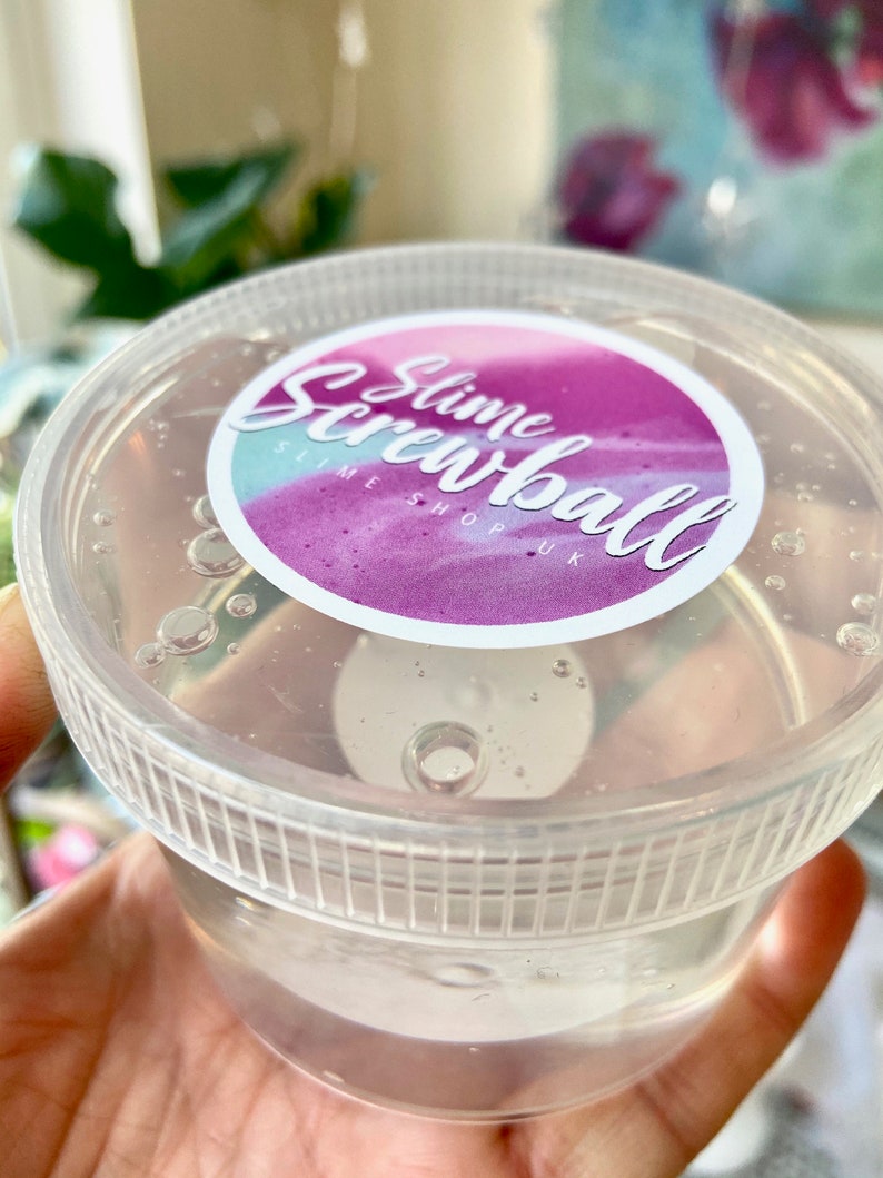 May include: A clear plastic container with a pink and purple label that says "Slime Screwball Slime Shop UK".