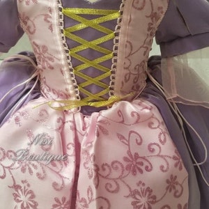 May include: A purple and pink princess dress with a gold ribbon corset and a floral pattern. The dress has a tulle overlay and is perfect for a little girl's costume.