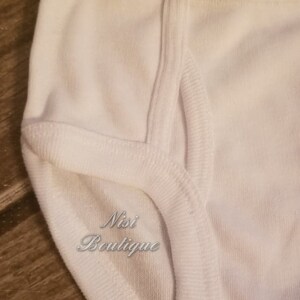 Pode incluir: Roupa interior de algod&atilde;o branco com uma costura dupla. A roupa interior tem o texto "Nisi Boutique" impresso na frente.