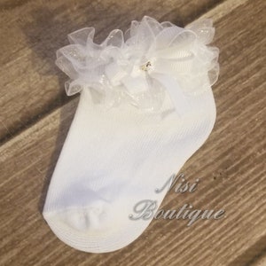 May include: White baby socks with a white lace ruffle and a small rhinestone bow.