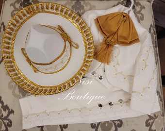 Pode incluir: Um traje de charro branco com bordados dourados e um chapéu branco a condizer com guarnição dourada. O traje inclui uma jaqueta, calças e um colete. O chapéu tem uma aba larga e uma coroa alta. O traje é decorado com padrões florais intrincados. O traje é um traje tradicional mexicano.
