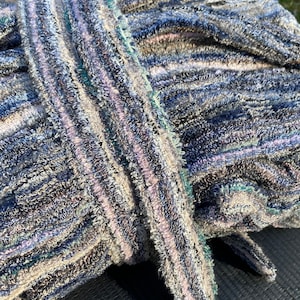 May include: A soft, striped robe with a plush texture. The robe is made of a thick, absorbent material and features a variety of colors, including blue, gray, and white.