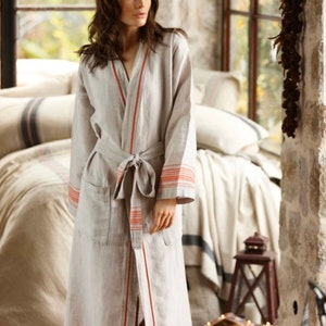 May include: A long, gray linen robe with red and white stripes. The robe has a sash tie and a pocket on the left side.