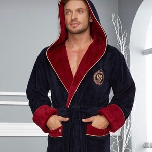 May include: A navy blue hooded robe with a red lining and gold trim. The robe features a large embroidered crest on the front.