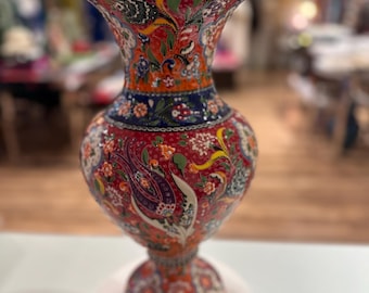 May include: A red, blue, and yellow ceramic vase with a floral pattern. The vase has a wide mouth and a narrow base.
