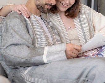 Op de afbeelding: Een stel zit op een bank, beiden dragen gestreepte gewaden en kijken samen naar een boek.