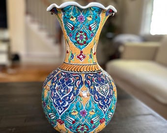 Può includere: Un vaso in ceramica giallo con un bordo ondulato e intricati motivi floreali blu, verdi e rossi.