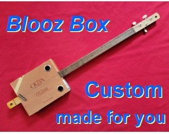 May include: A custom-made cigar box guitar, also known as a "blooz box", with a wooden body and a single string. The guitar is made from a repurposed cigar box and has a simple design.