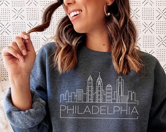 May include: A dark blue sweatshirt with a white outline of the Philadelphia skyline and the word "PHILADELPHIA" underneath.