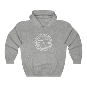 May include: Grey hooded sweatshirt with a white outline of a circle containing the words "North Carolina" and "Esse Quam Videri" with a mountain and tree design.