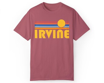 May include: A maroon t-shirt with a retro-style graphic design featuring a yellow sun, blue, orange, and red stripes, and the word "IRVINE" in yellow letters.