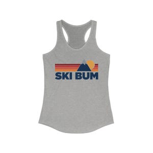 May include: Gray tank top with a retro-style graphic of a mountain, sun, and the text "SKI BUM" in blue.