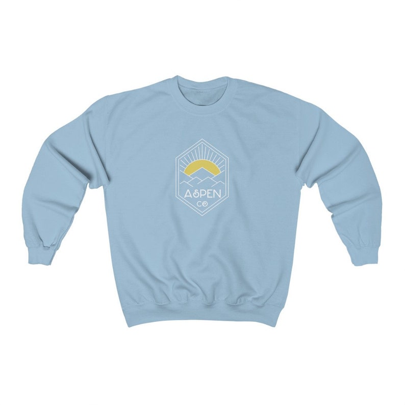 May include: Light blue sweatshirt with a white graphic of a mountain range with a sun rising behind it. The graphic is inside a hexagon with the text "ASPEN CO" below it.