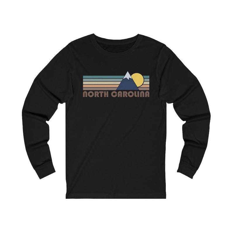 May include: Black long-sleeve t-shirt with a retro-style graphic of a mountain range, sun, and the text "NORTH CAROLINA".