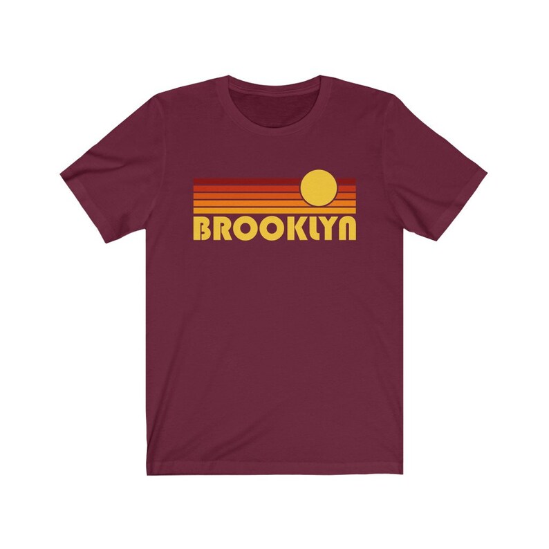 May include: A maroon t-shirt with a retro sunset graphic and the word "BROOKLYN" in yellow.
