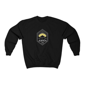 May include: Black sweatshirt with a white graphic of a mountain range with a sun rising behind it. The graphic is inside a hexagon with the text "ASPEN CO" below it.