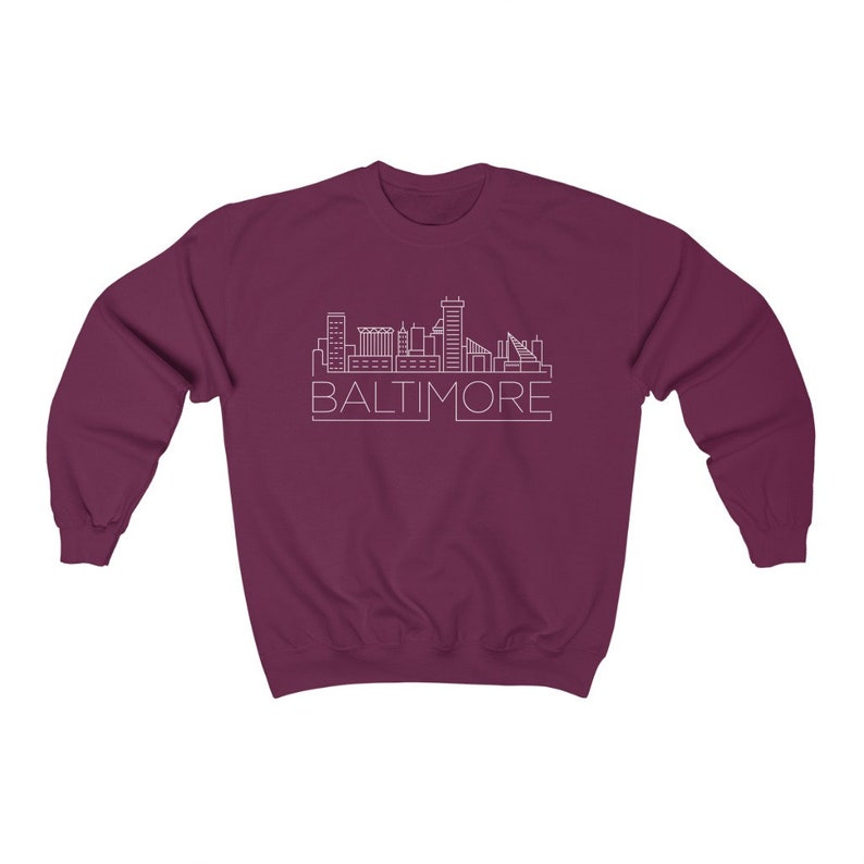 May include: A maroon sweatshirt with a white outline of the Baltimore skyline and the word "BALTIMORE" underneath.