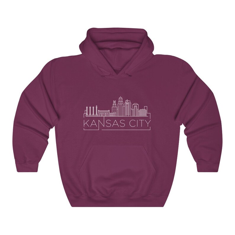 Może przedstawiać: Bordowa bluza z kapturem z białym obrysem panoramy Kansas City i napisem "KANSAS CITY" poniżej. Bluza ma przednią kieszeń i kaptur.
