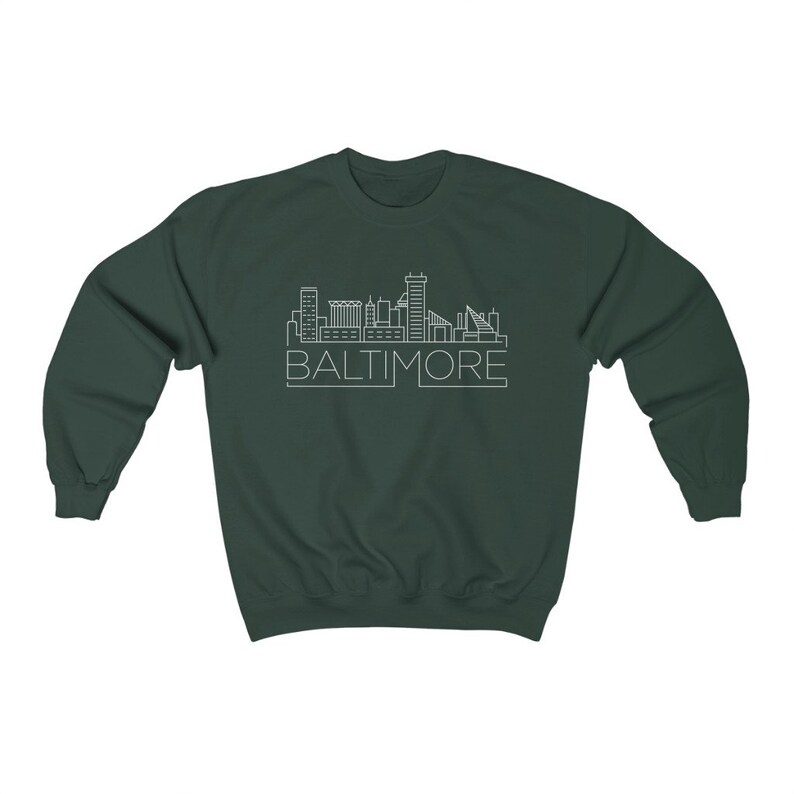 May include: A dark green sweatshirt with a white outline of the Baltimore skyline and the word "BALTIMORE" underneath.