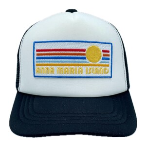 May include: A white and black trucker hat with an embroidered patch that says "Anna Maria Island" and features a yellow sun and colorful stripes.