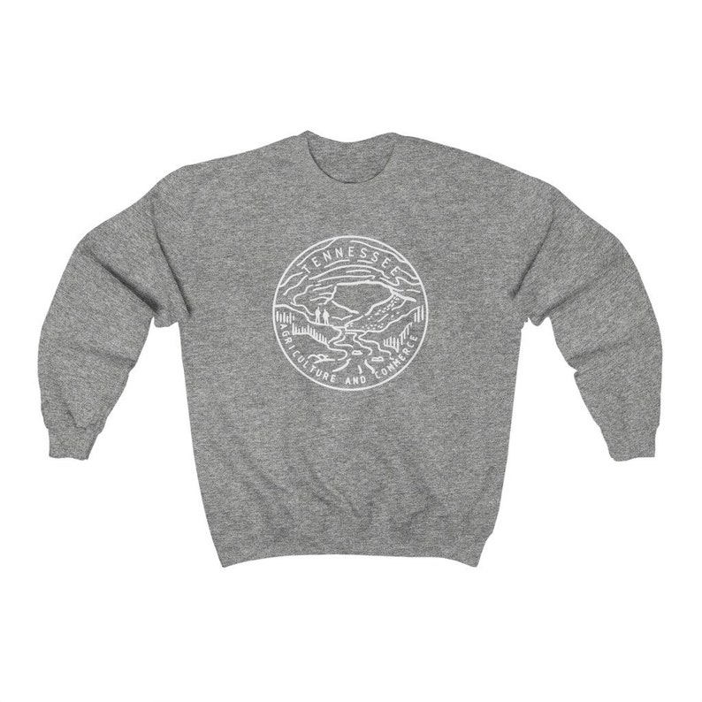 May include: A gray sweatshirt with a white outline of the state of Tennessee seal. The seal features a mountain range, a river, and the words "Agriculture and Commerce".