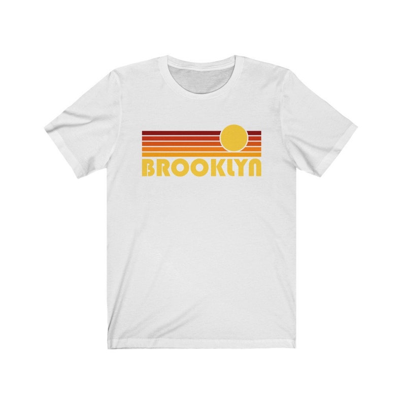 May include: White t-shirt with a retro sunset graphic and the word "BROOKLYN" in yellow.