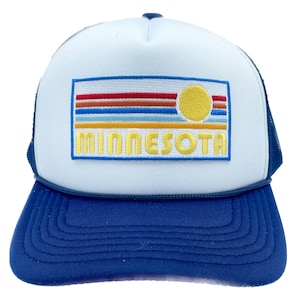 May include: A white trucker hat with a blue mesh back. The front of the hat features a blue, yellow, red, and orange embroidered patch with the words "MINNESOTA" and a stylized sun.