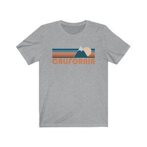 May include: A heather gray t-shirt with a retro-style graphic of a mountain range, sun, and the word "CALIFORNIA" in orange.