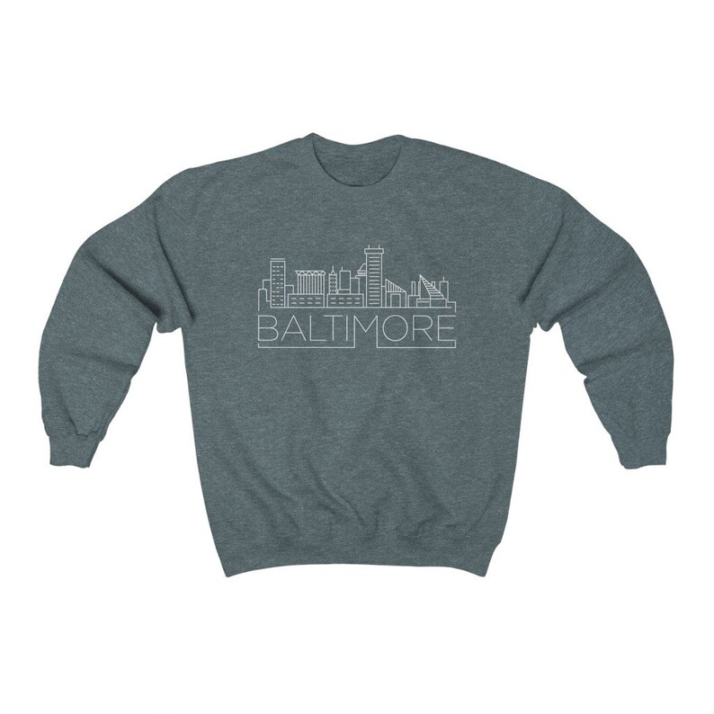 May include: A dark heather grey sweatshirt with a white outline of the Baltimore skyline and the word "BALTIMORE" printed below it.