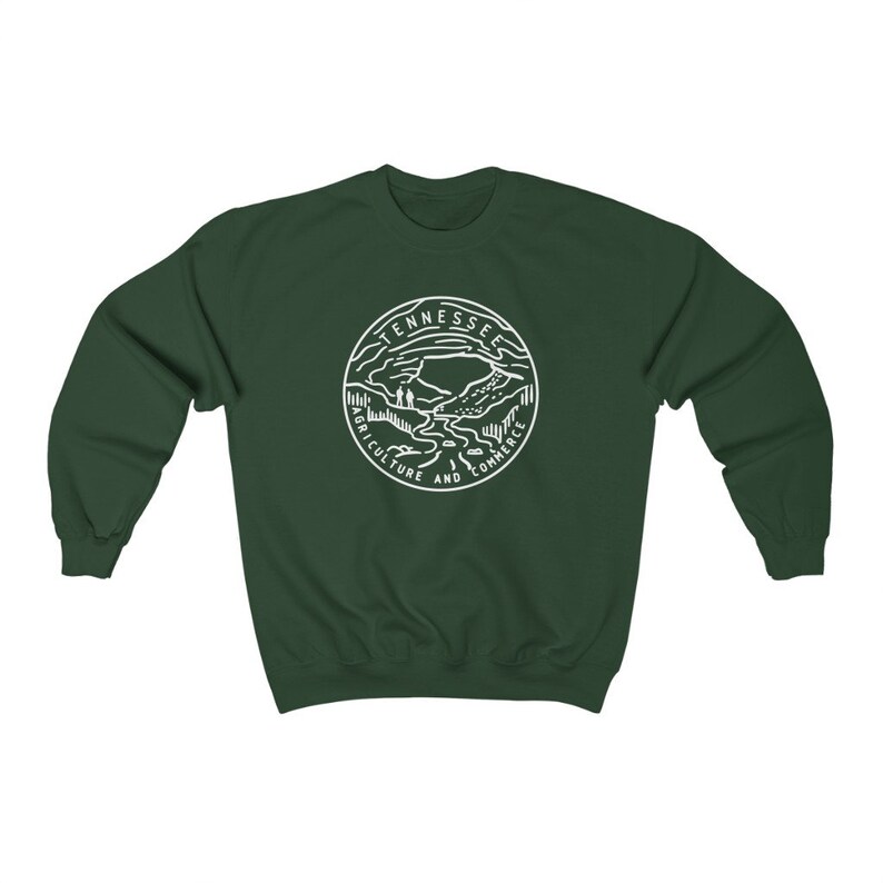 May include: A dark green sweatshirt with a white outline of the state of Tennessee seal. The seal features a mountain range, a river, and the words "Agriculture and Commerce".