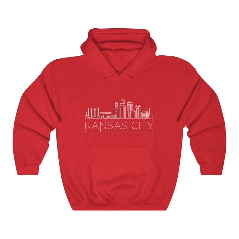 Może przedstawiać: Czerwona bluza z kapturem z białym rysunkiem linii horyzontu Kansas City. Tekst "KANSAS CITY" jest wydrukowany na biało pod projektem. Bluza ma przednią kieszeń i kaptur ze sznurkiem.