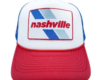 May include: A white and red trucker hat with a blue and white striped patch that says "nashville" in red letters.