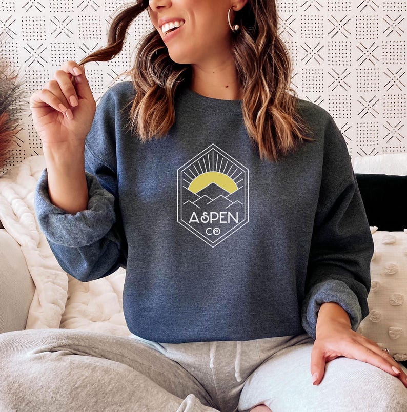 May include: A dark blue sweatshirt with a white graphic of a mountain range and a sun with the text "Aspen Co."