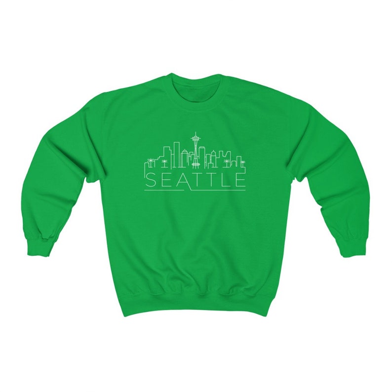 May include: A green sweatshirt with a white outline of the Seattle skyline and the word "SEATTLE" underneath.