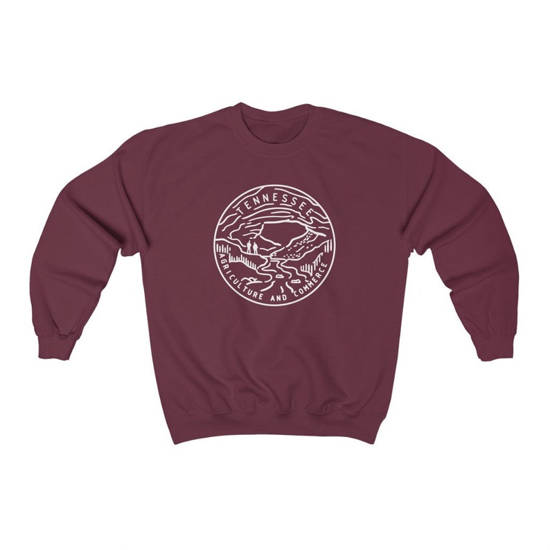 May include: Burgundy sweatshirt with a white outline of the state of Tennessee seal. The seal features a mountain range, a river, and the words "Agriculture and Commerce".