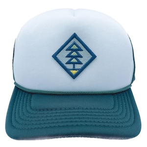 May include: A light blue trucker hat with a green mesh back. The front of the hat features a diamond-shaped patch with an embroidered green, yellow, and blue tree design.