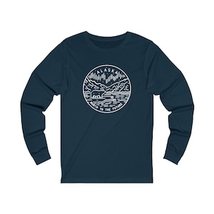 May include: A navy blue long-sleeve t-shirt with a white graphic design of a bear in front of a mountain range with the text "Alaska North to the Future".