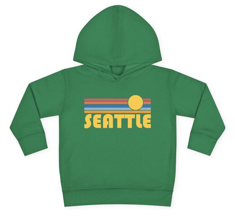 Pode incluir: Uma jaqueta de moletom verde para crian&ccedil;as pequenas com um gr&aacute;fico de p&ocirc;r do sol retr&ocirc; e a palavra "SEATTLE" em letras amarelas.