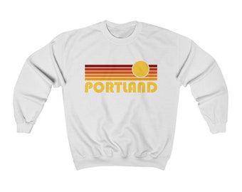 May include: White sweatshirt with a retro-style graphic of a sunset with the word "PORTLAND" in yellow text.