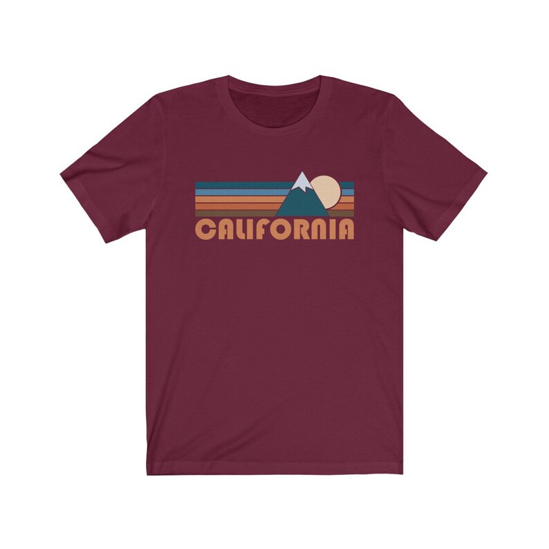 May include: A maroon short-sleeved t-shirt with a retro-style graphic of a mountain range, sun, and the word "CALIFORNIA" in orange.