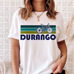 May include: White t-shirt with a retro-style graphic of a bicycle with the word "DURANGO" printed below it.