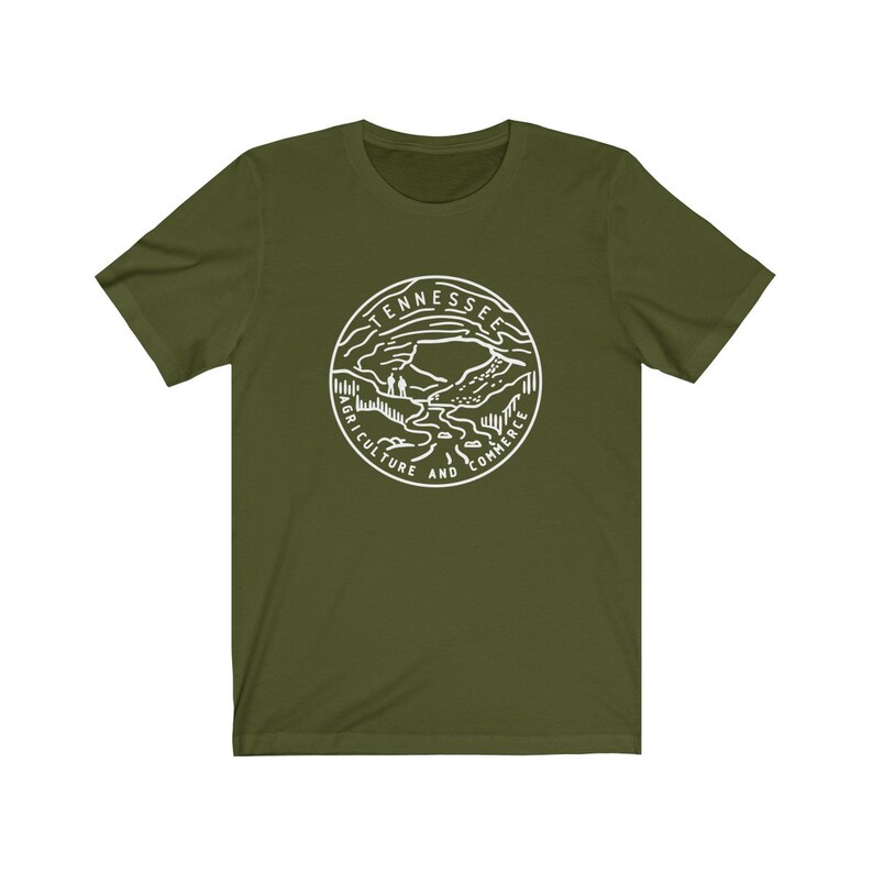 May include: A green t-shirt with a white outline of the state of Tennessee seal. The seal features a mountain range, a river, and the words "Agriculture and Commerce".
