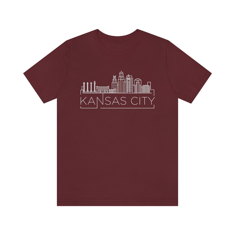 May include: A maroon t-shirt with a white outline of the Kansas City skyline and the text "KANSAS CITY" underneath.