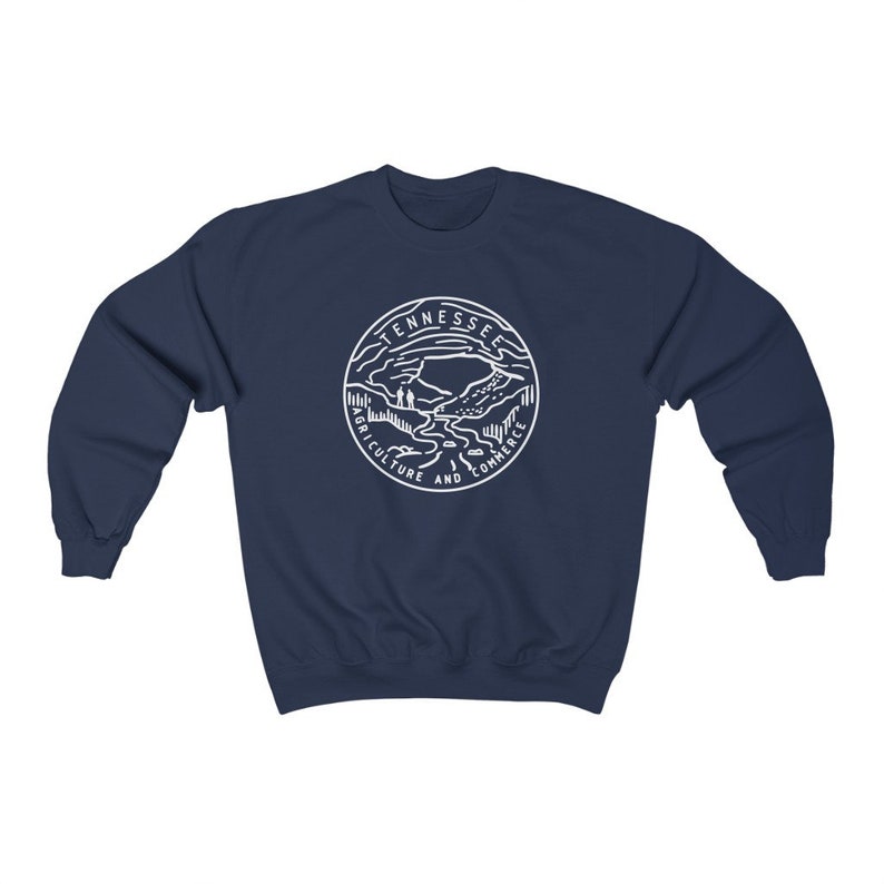 May include: Navy blue sweatshirt with a white graphic of the Tennessee state seal. The seal features a mountain range, a river, and the words "Agriculture and Commerce".